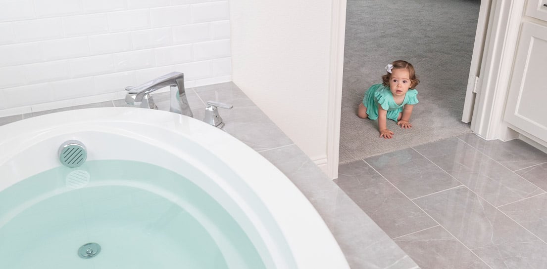toddler girl crawling toward undrained bathtub